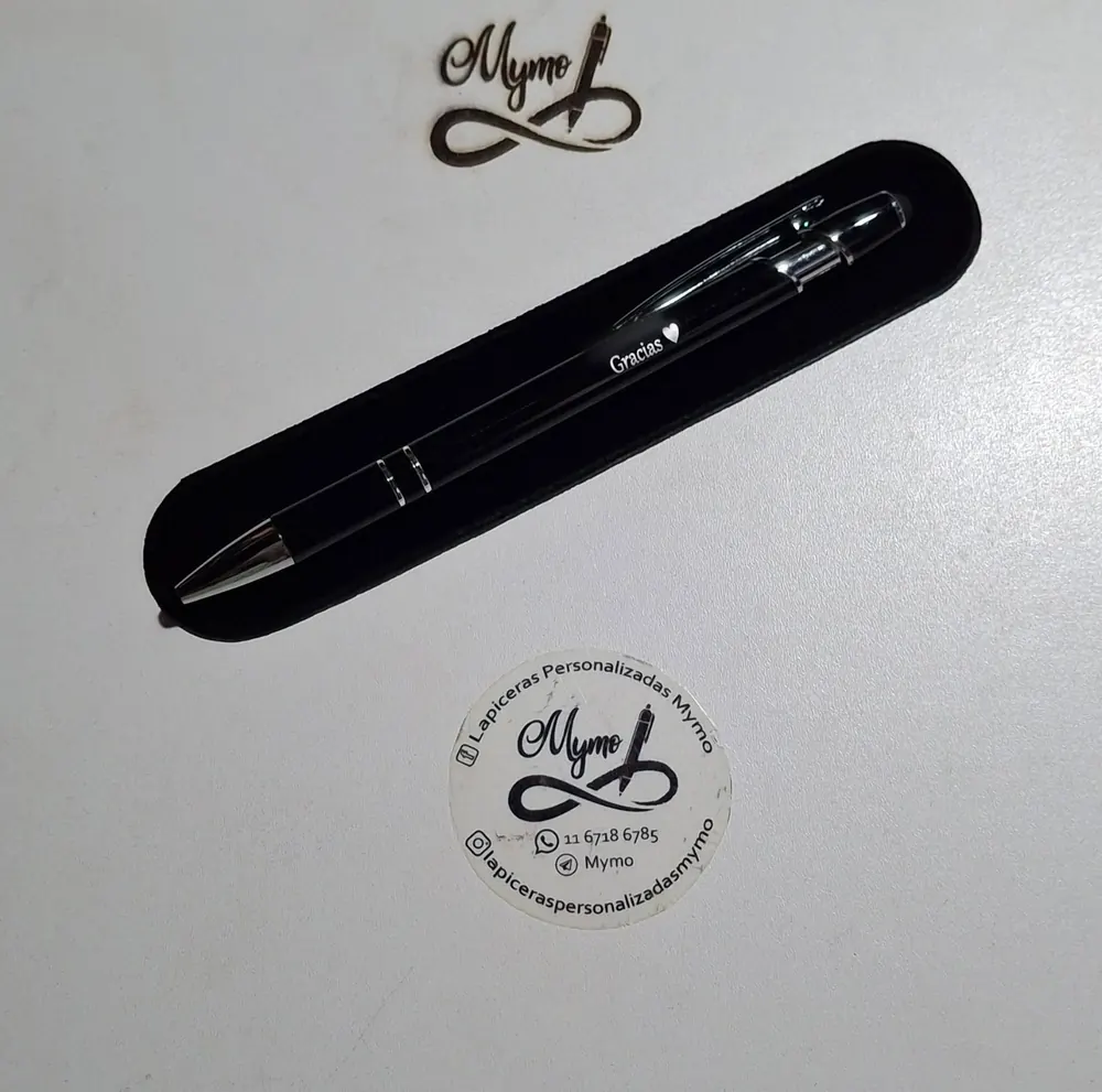 Una lapicera metálica negra grabada con «Gracias» y un corazón, en su funda